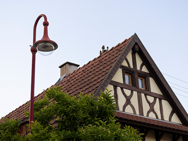 Rote Glockenleuchte mit LED, im Hintergrund Blick auf den Dachfirst eines Fachwerkhauses